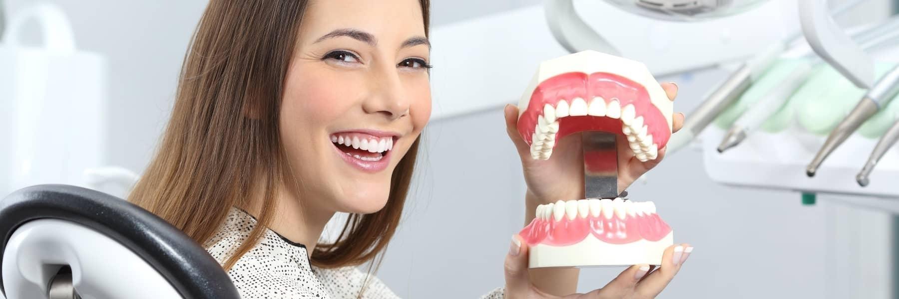 Patient holding model of teeth at dentist in Denver CO